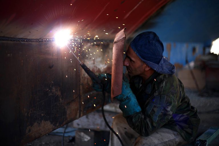 Man Holding Welding Rod and Welding Mask While Working